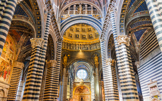 Innenansicht einer Kirche mit Säulen und kunstvollem Gewölbe.