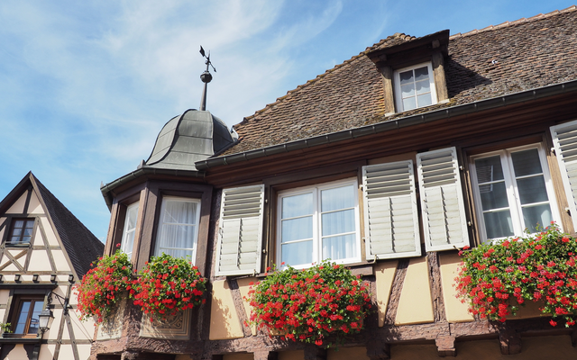 Fachwerkhaus mit blühenden Blumenkästen unter blauem Himmel.