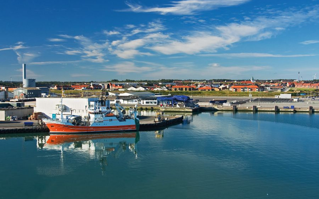 Hafenansicht mit blauem Himmel und Schiff im Vordergrund.