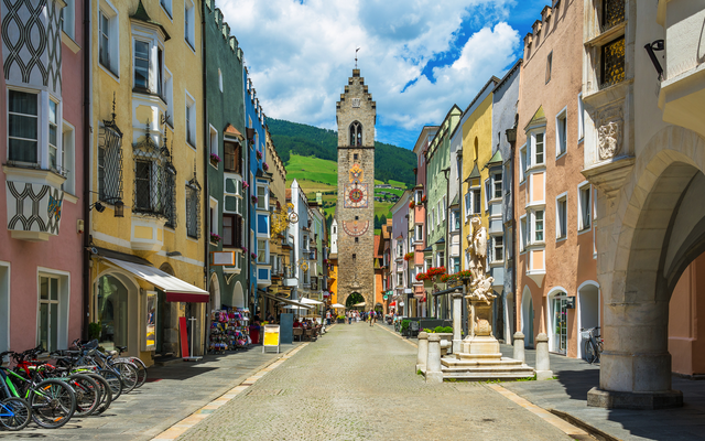 Bunte Häuser und Uhrenturm in einer historischen Altstadtstraße.