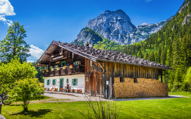 Holzhaus in alpenländischer Landschaft vor Berg in sommerlicher Umgebung