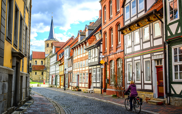 Eine Straße mit Fachwerkhäusern und einem Kirchturm im Hintergrund.