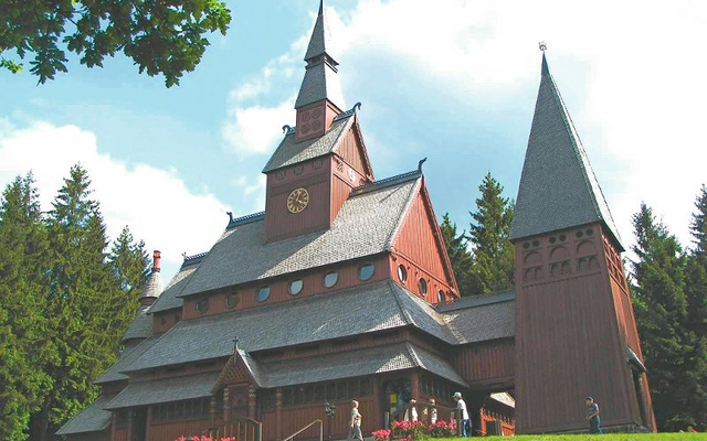 Stabkirche in Hahnenklee, umgeben von Bäumen und Wiese.