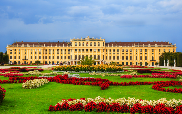 Barockschloss mit aufwendig gestalteten Blumenbeeten im Vordergrund.