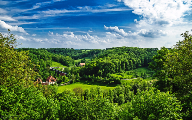 Landschaft mit grünen Hügeln und blauem Himmel.