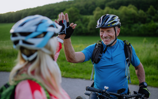 Zwei Radfahrer geben sich unterwegs einen High-Five.