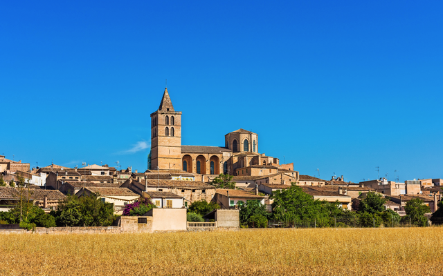 Landschaft mit historischer Kirche und blauen Himmel im Hintergrund.