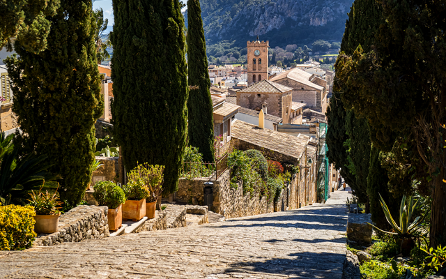 Malerische Treppe in mediterranem Dorf mit Zypressen und Kirche im Hintergrund