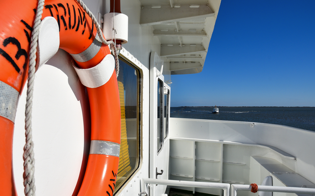 Rettungsring an Bord eines Schiffs mit Blick auf das Meer und blauen Himmel.
