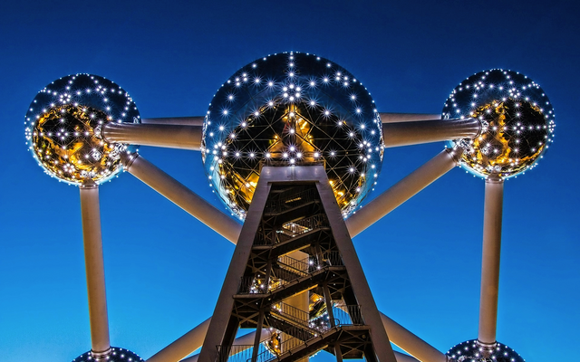 Metallstruktur des Atomiums bei Nacht mit beleuchteten Kugeln und blauem Himmel.