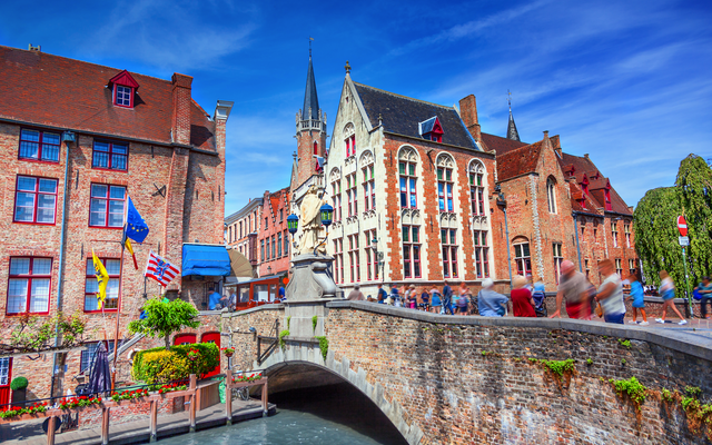 Mittelalterliche Gebäude und Kanal mit Brücke bei sonnigem Wetter in Brügge, Belgien.