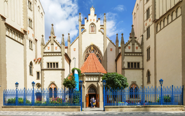 Historisches Gebäude mit reich verzierter Fassade und Eingangstor, umgeben von blauem Zaun.