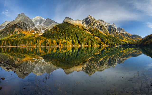 Berglandschaft mit Herbstwald spiegelt sich in einem ruhigen See.