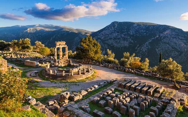 Ruinen in Delphi vor Bergkulisse bei Sonnenuntergang