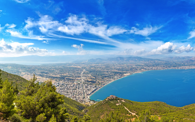 Panorama einer Küstenstadt mit blauem Meer und verdeckten Hügeln.