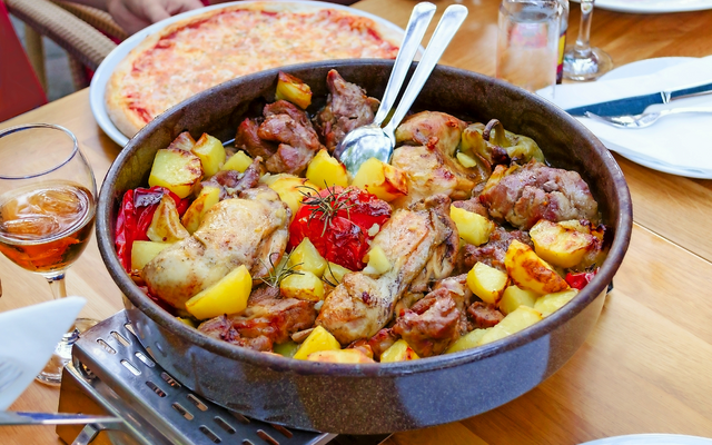Bräter mit gebratenem Hähnchen, Kartoffeln und Paprika auf einem Tisch.