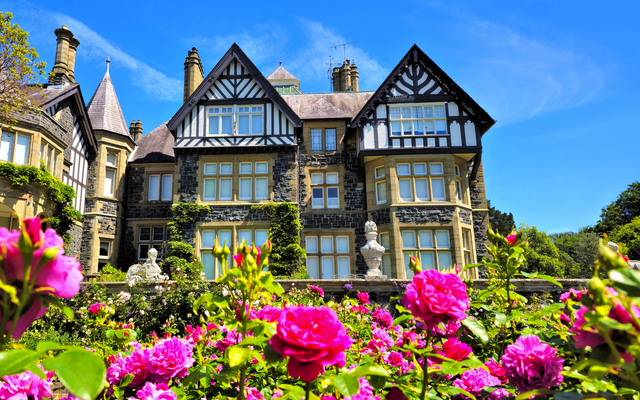 Herrenhaus im Tudor-Stil mit blühendem Garten im Vordergrund