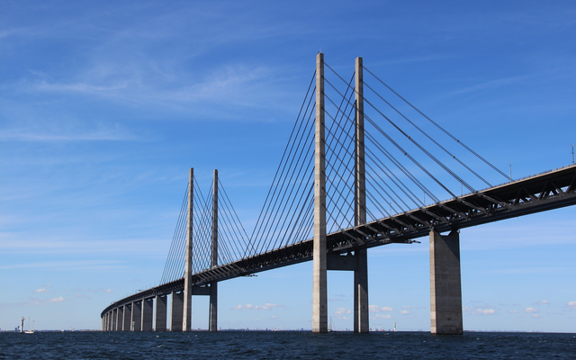 Eine große, moderne Brücke erstreckt sich über ein Gewässer unter einem klaren blauen Himmel.