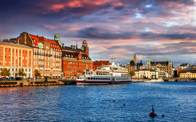 Hafen in einer Stadt mit Gebäuden am Wasser bei Sonnenuntergang.