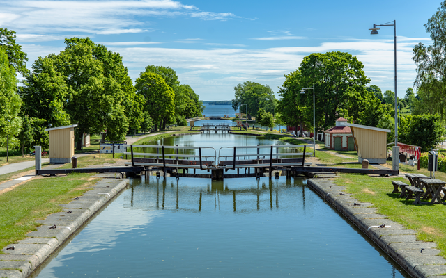 Kanal mit Schleusen und Bäumen an einem sonnigen Tag.