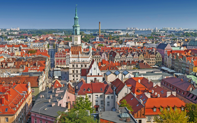 Panorama einer historischen Altstadt mit roten Dächern und einem Turm im Zentrum.