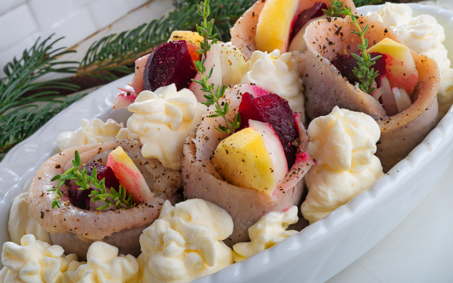 Gerichte mit Heringsröllchen, Rote Beete, Äpfeln und Kräutern auf Sahne.