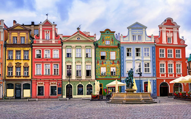 Bunte Renaissancefassaden am zentralen Marktplatz in Posen mit einer Brunnenskulptur im Vordergrund.