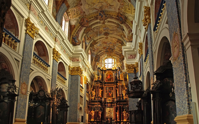 Innenansicht einer prunkvoll verzierten Barockkirche mit Altar und Fresken an der Decke.