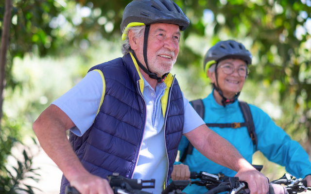 Älteres Paar mit Helmen beim Radfahren im Freien.