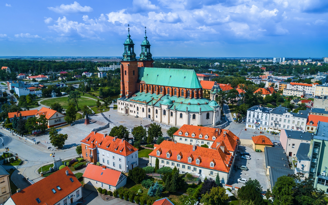 Luftaufnahme einer Kathedrale mit zwei Türmen in einer Stadt mit roten Dächern.