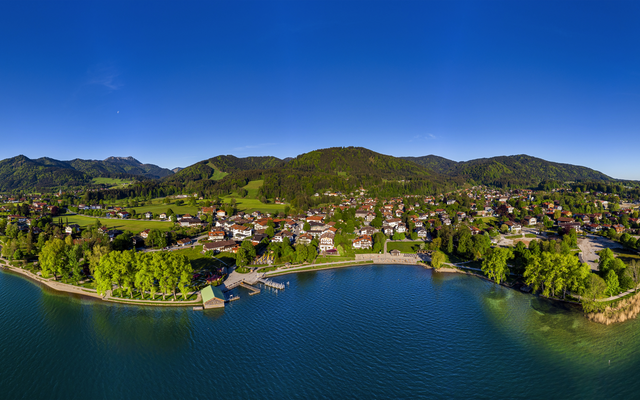 Luftaufnahme einer malerischen Küstenstadt mit Bergen im Hintergrund.