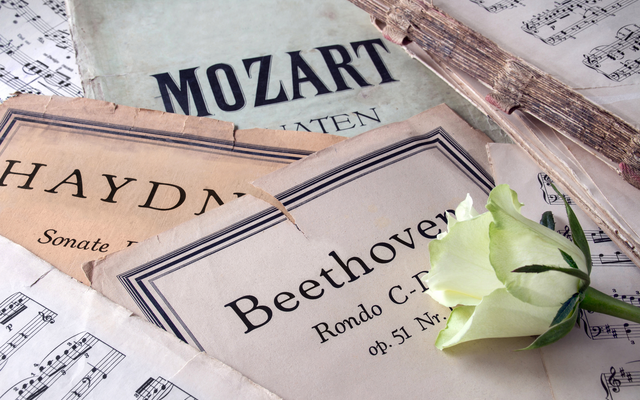 Notenblätter von Mozart, Haydn und Beethoven mit einer weißen Rose.