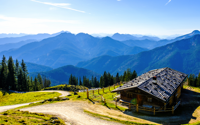 Berghütte auf einer Wiese mit Bergpanorama im Hintergrund