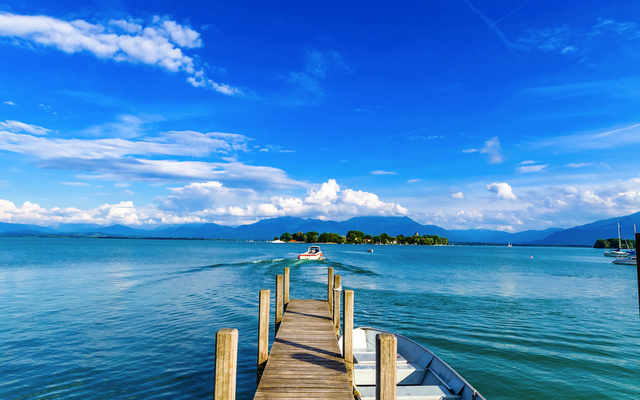 Holzsteg zum See mit kleinem Motorboot, Himmel mit Wolken.