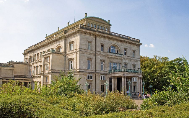 Großes historisches Gebäude mit Säulen und Pflanzen im Vordergrund.