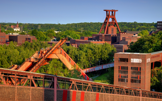Industriekultur mit Förderturm und grüner Umgebung bei Sonnenschein.