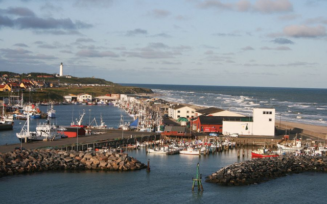 Hafenansicht von Hirtshals, Dänemark, mit Leuchtturm und Fischerbooten.