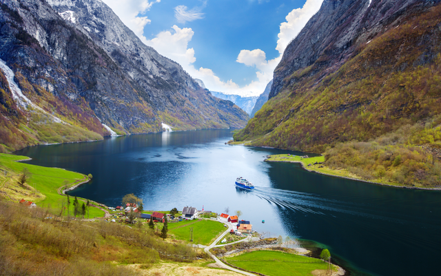 Ein Fjord mit einem Schiff und umliegenden Bergen.