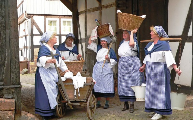 Gruppe von Frauen in traditioneller Kleidung mit Waschutensilien im Freien.