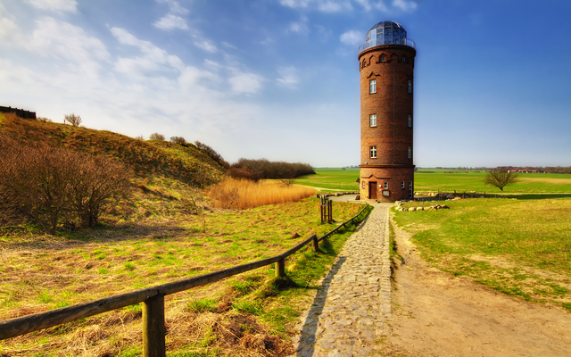 Runder Ziegelturm auf einem Feld mit klarem Himmel.
