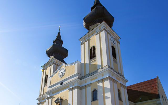 Barockkirche mit zwei Zwiebeltürmen unter blauem Himmel.