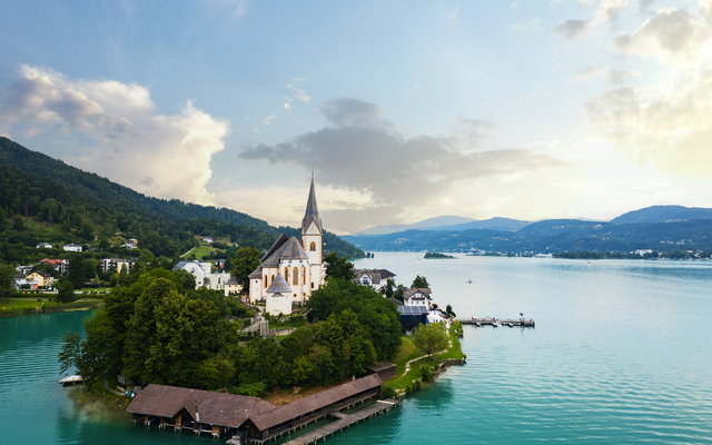 Luftaufnahme einer Kirche auf einer Insel in einem See mit umliegenden Bergen.