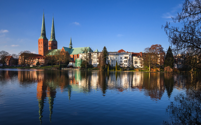 Stadtansicht mit Kirche und Spiegelung im Wasser bei klarem Himmel.