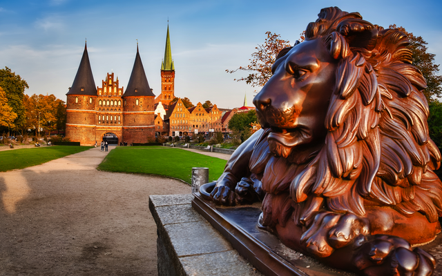 Backstein-Löwenstatue vor dem Holstentor in Lübeck bei Sonnenuntergang.