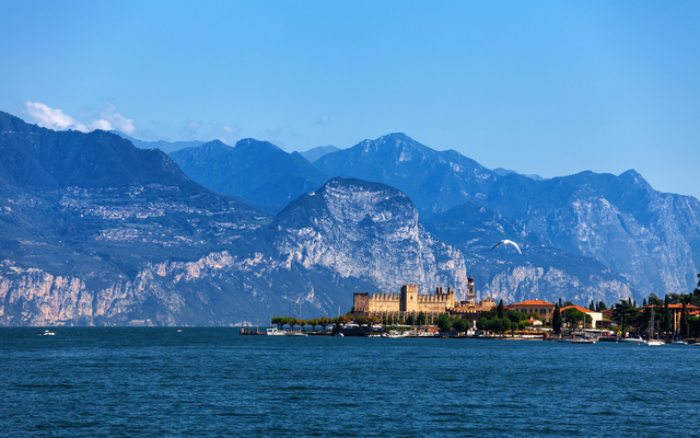 Burg am See mit Bergkulisse im Hintergrund.