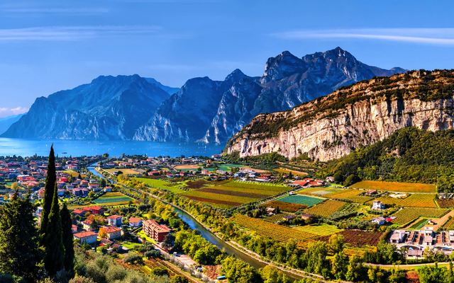 Panorama einer Berglandschaft mit See, Dörfern und Weinbergen im Vordergrund.