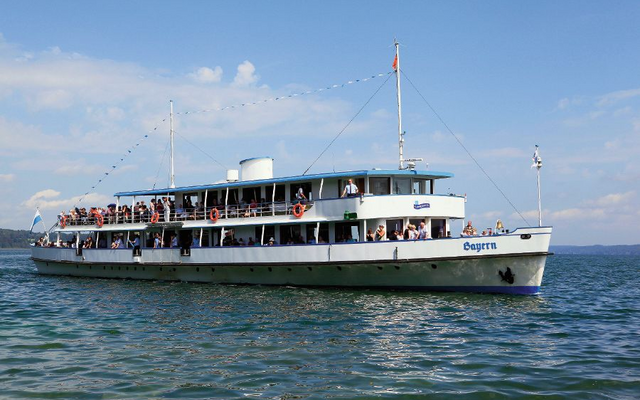 Ausflugsschiff Bayern auf dem Starnberger See vor bewölktem Himmel, viele Menschen an Bord.
