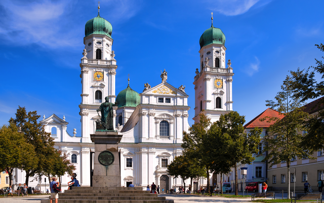 Historische Kathedrale mit zwei Türmen, blauem Himmel und Bäumen im Vordergrund.