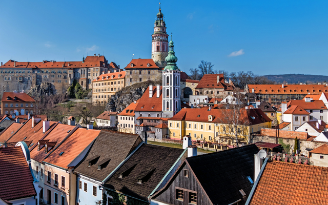 Panorama einer historischen Stadt mit Burg und roten Dächern bei sonnigem Wetter.