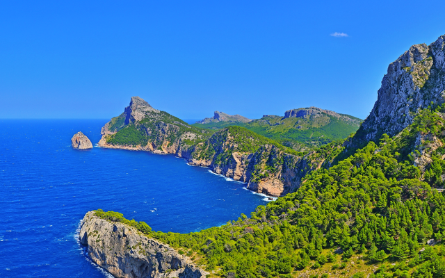 Küste mit Felsen und blauem Meer unter klarem Himmel.